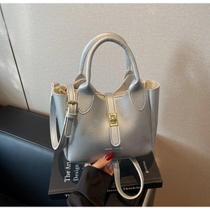 Detail of silver bucket bag with lychee leather texture and golden twist-lock closure