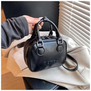 Detailed macro view of the glossy black retro embossed pattern on the leather handbag