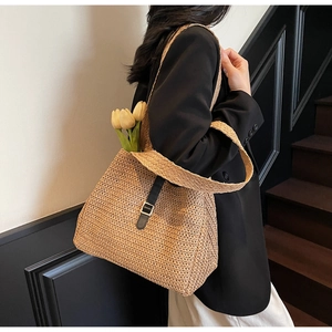 Détail de la texture tissée et de la bandoulière en cuir noir du sac cabas en paille tressée