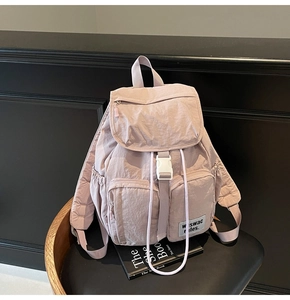 Detail of light purple nylon backpack with white buckles and front zipper pockets