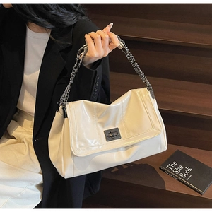 Detail of soft leather tote bag showing shiny patent finish and elegant metal chain strap
