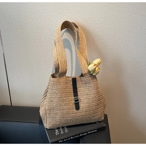 Détail d'un sac cabas en paille tressée avec sangle en cuir noir et boucle en métal