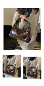 Detail of glossy brown oil wax leather handbag with embossed lettering and shoulder strap