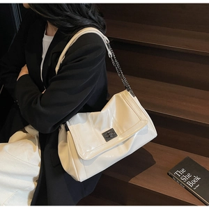 Detail of soft leather tote bag with black metallic turn-lock and chain strap on stairs