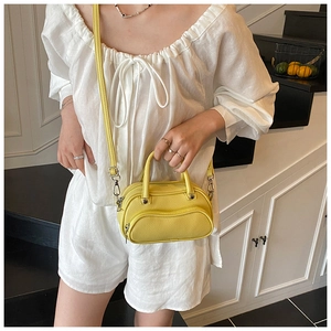 Bright yellow lychee leather mini crossbody bag shown on a model with white linen outfit