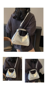 Detail view of silver PU leather handbag showing the embossed logo and metal strap clips