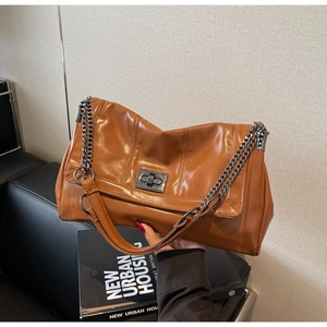 Detail of caramel brown faux leather tote with metallic turn-lock and chain strap