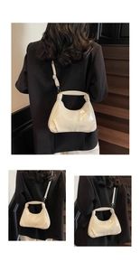 Detail view of cream patent leather crescent handbag with embossed text and wide top handle