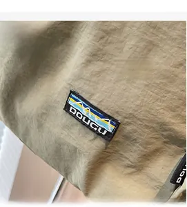 Détail du sac à dos en nylon kaki avec écusson de montagne brodé et cordon de serrage