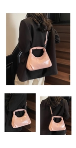 Detailed close-up of glossy pink crescent bag with textured letter embossing and fine strap