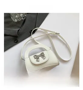 Top view of white lychee leather mini crossbody bag with silver metal bow hardware detail