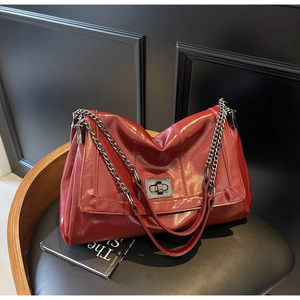 Close-up of red oil-wax leather tote bag with glossy finish and metal twist lock