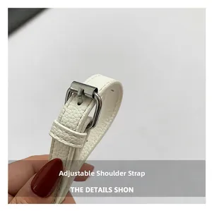 Macro view of adjustable white lychee pattern leather shoulder strap with silver metal buckle