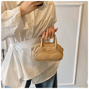 Detail of khaki litchi grain mini Boston bag showing metallic hardware and outer zip pocket