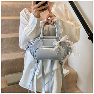 Close-up of light blue patent leather Boston bag with lace bow and pearl charm detail