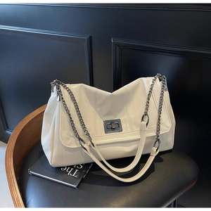 Detail of white glossy chain bag featuring a dark grey metal twist lock on a chair