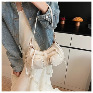 Close-up of functional golden zippers and pocket details on cream white motor-style bag