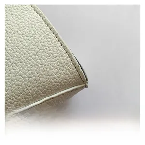 Detailed macro shot of white lychee textured leather and stitching on the crossbody bag