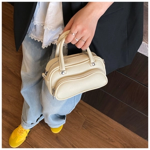 Detailed top view of a cream lychee-textured boston bag with metallic zipper and top handles