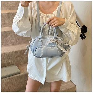 Detail of light blue glossy handbag with pearl bow charm and delicate lace ribbon
