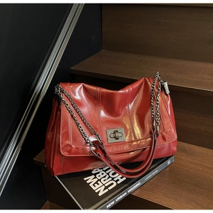 Close-up of red vintage oil wax leather tote bag with silver twist lock and chain strap
