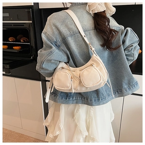 Model wearing the cream crescent underarm bag with double zipper pockets in a kitchen