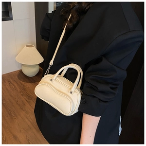 Close-up of beige lychee texture leather mini crossbody bag with top handles on model