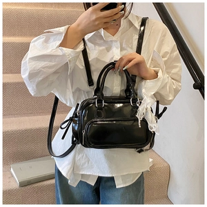 Glossy black patent leather Boston bag detail with white lace charm and straps