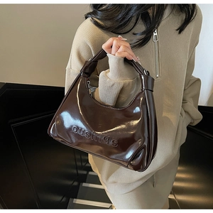 Detail of dark brown oil wax leather handbag with knotted handle and embossed logo