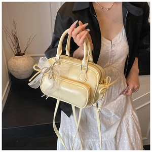 Detail view of cream-colored Boston bag with pearl mesh bow and polished finish