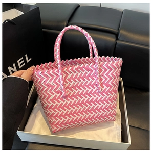 Close-up of pink and white woven tote bag with a trapezoid shape and round handles