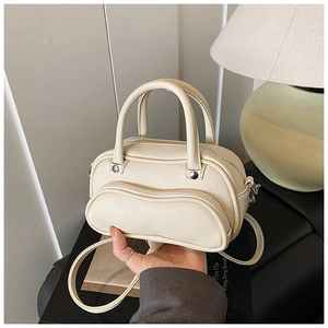 Close-up of cream lychee texture crossbody bag featuring a wavy zipper pocket and dual handles