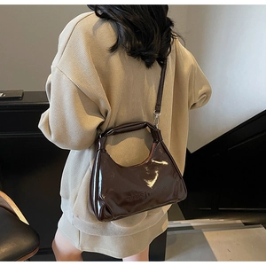 Macro shot of glossy chocolate oil-wax leather hobo bag with a sleek adjustable strap