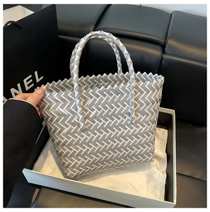 Detail view of woven tote bag with grey and white pattern and reinforced round handles