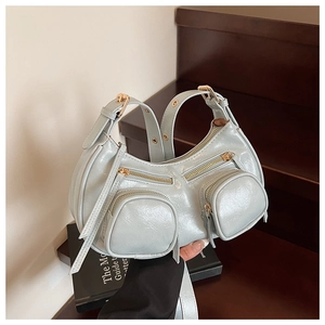 Detail of light blue crescent underarm bag with glossy crinkled texture and gold zippers