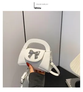 Detailed view of mini white pebbled leather bag with silver metallic bow and fine strap