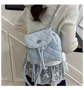 Detail of light blue quilted leather backpack with silver twist lock and chain strap