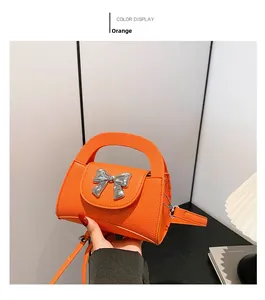 Detail of orange lychee leather bag with silver metal bow and detachable shoulder strap