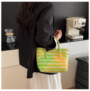 Lifestyle shot of a green and yellow woven tote bag paired with a modern outfit