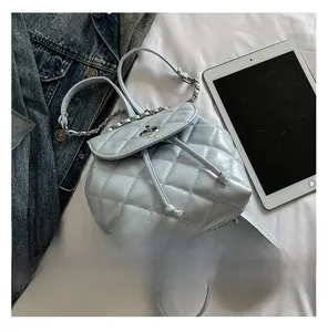 Close-up of light blue quilted mini backpack featuring metal chain straps and twist lock