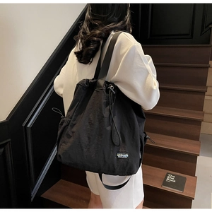 Détail du sac fourre-tout noir en nylon avec cordon de serrage et étiquette DOUGU