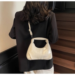 Detailed view of cream oil-wax leather hobo bag with oushide embossing on a staircase