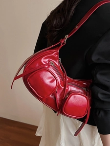 Red patent leather punk style shoulder bag with multiple zippers shown on a model