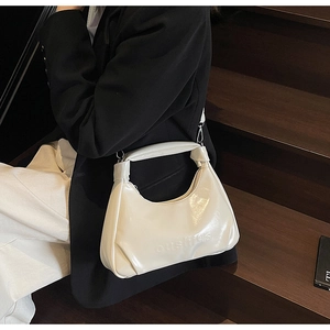 Detail of creamy white waxed leather texture and debossed lettering on shoulder bag