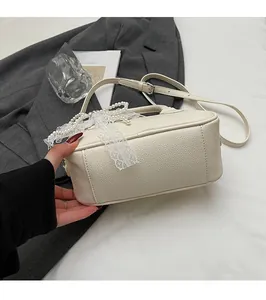 Close-up of cream leather bag with pearl bow, lace trim and elegant metal buckle details