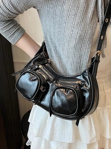 Glossy black crescent shoulder bag with metallic gold zippers and punk style details
