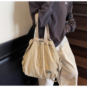 Détail du sac cabas en nylon kaki avec cordon de serrage et poches latérales à l'extérieur