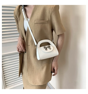 Detailed view of a white bow crossbody bag showing silver bow and pebble leather texture