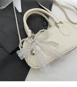 Detail of off-white lychee leather Boston bag with pearl lace bow and fashion embossing