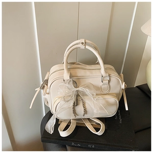 Detail of beige Boston bag featuring lace bow, silver pearls, and dual zipper design